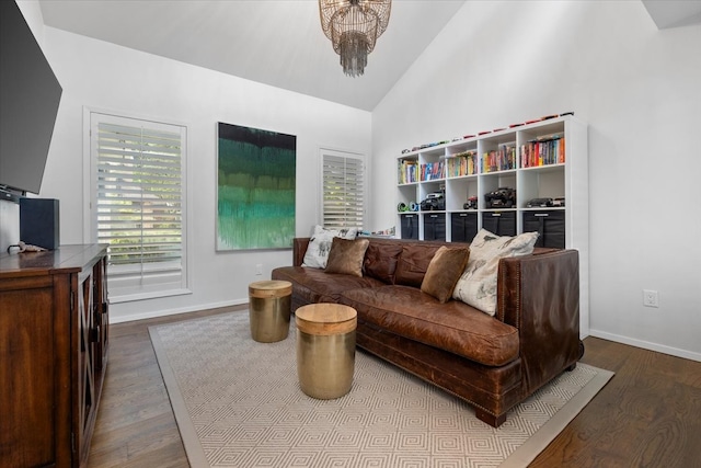 living area with dark wood finished floors, baseboards, high vaulted ceiling, and a chandelier