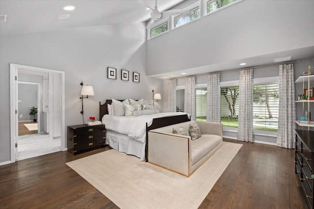 bedroom featuring dark wood-style floors, a high ceiling, and baseboards