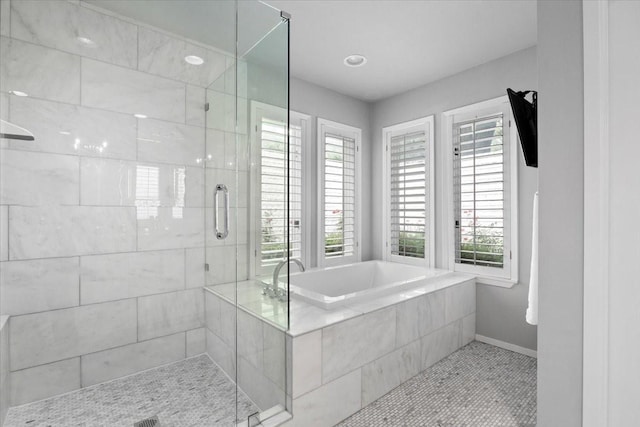 bathroom featuring a stall shower, a bath, tile patterned floors, and baseboards