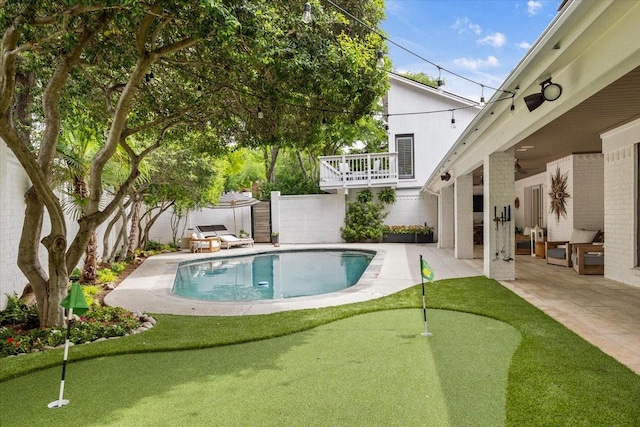 swimming pool with an area to practice putting, a patio area, and a fenced backyard