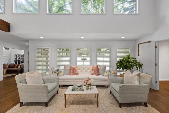 living room featuring plenty of natural light, a towering ceiling, recessed lighting, and wood finished floors