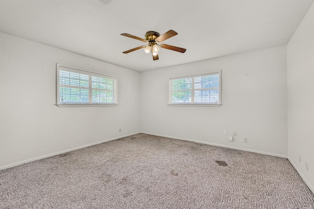 carpeted spare room with healthy amount of natural light, a ceiling fan, and baseboards