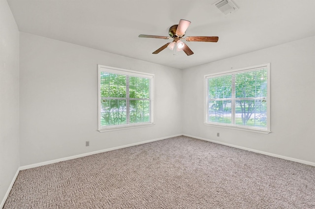 carpeted spare room with healthy amount of natural light, a ceiling fan, and baseboards