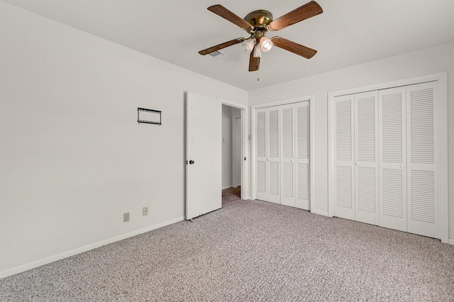unfurnished bedroom with carpet floors, multiple closets, baseboards, and a ceiling fan