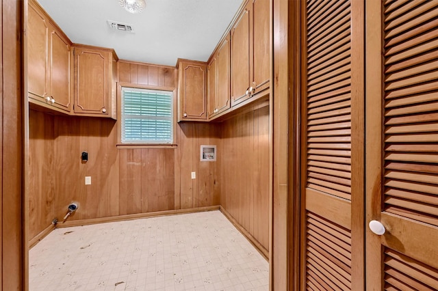 washroom featuring washer hookup, electric dryer hookup, cabinet space, wooden walls, and light flooring