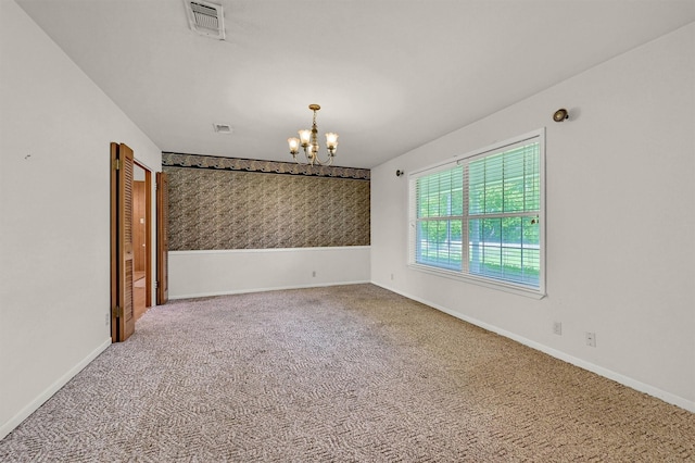 carpeted empty room with a chandelier and baseboards