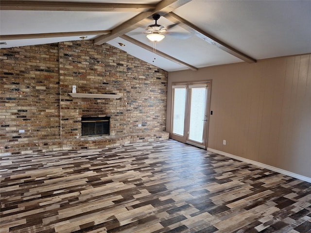 unfurnished living room with wood finished floors, a ceiling fan, a fireplace, baseboards, and brick wall