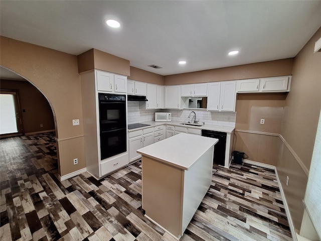 kitchen with black appliances, a sink, wood finished floors, white cabinetry, and recessed lighting