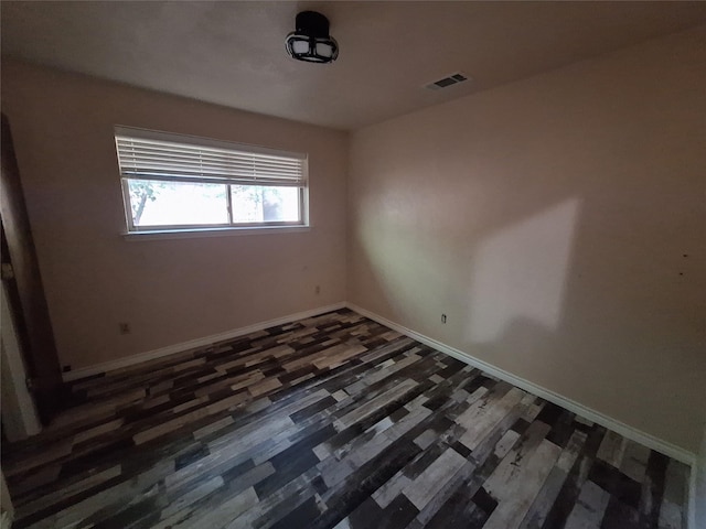 spare room with baseboards and wood finished floors