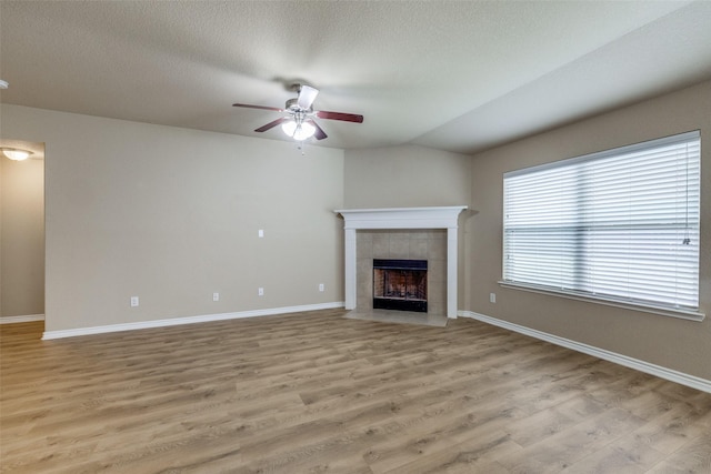 5844 Sunny Meadow Ln, Grand Prairie, TX 75052 - unfurnished living room featuring ceiling fan, a fireplace, light wood-style floors, baseboards, and a textured ceiling