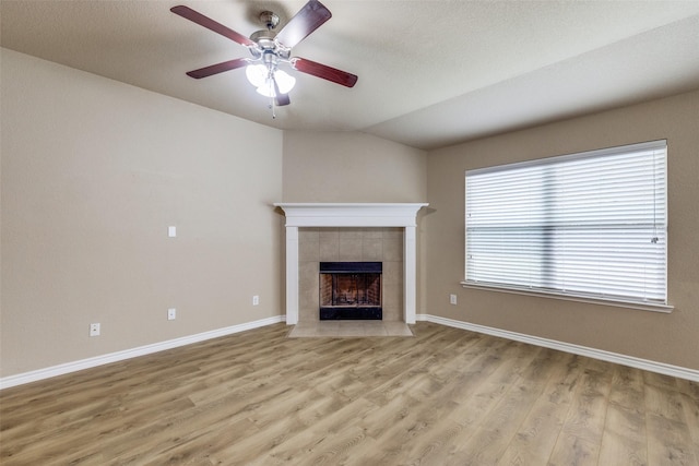 5844 Sunny Meadow Ln, Grand Prairie, TX 75052 - unfurnished living room with a tiled fireplace, a ceiling fan, light wood-type flooring, baseboards, and lofted ceiling