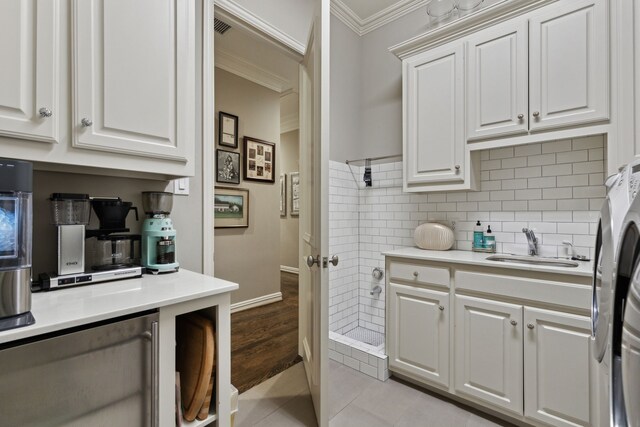 3725 Turtle Creek Blvd Unit A, Dallas, TX 75219 - kitchen with a sink, ornamental molding, light countertops, white cabinetry, and light tile patterned flooring