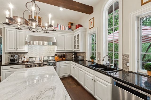 3725 Turtle Creek Blvd Unit A, Dallas, TX 75219 - kitchen with wall chimney range hood, appliances with stainless steel finishes, a sink, a chandelier, and white cabinets
