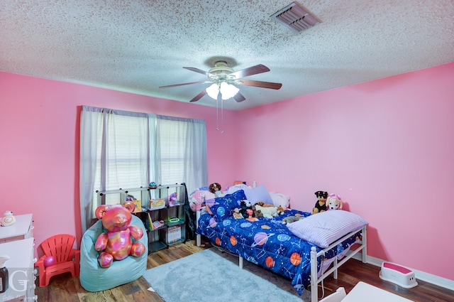 bedroom featuring a textured ceiling, wood finished floors, a ceiling fan, and baseboards