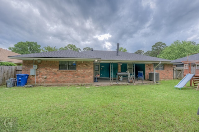 rear view of property featuring brick siding, a patio area, cooling unit, a shingled roof, and a playground