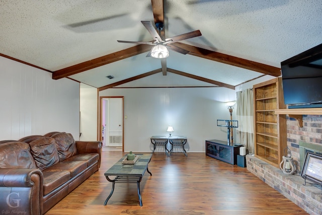 living area with wood finished floors, a textured ceiling, a fireplace, a ceiling fan, and built in features