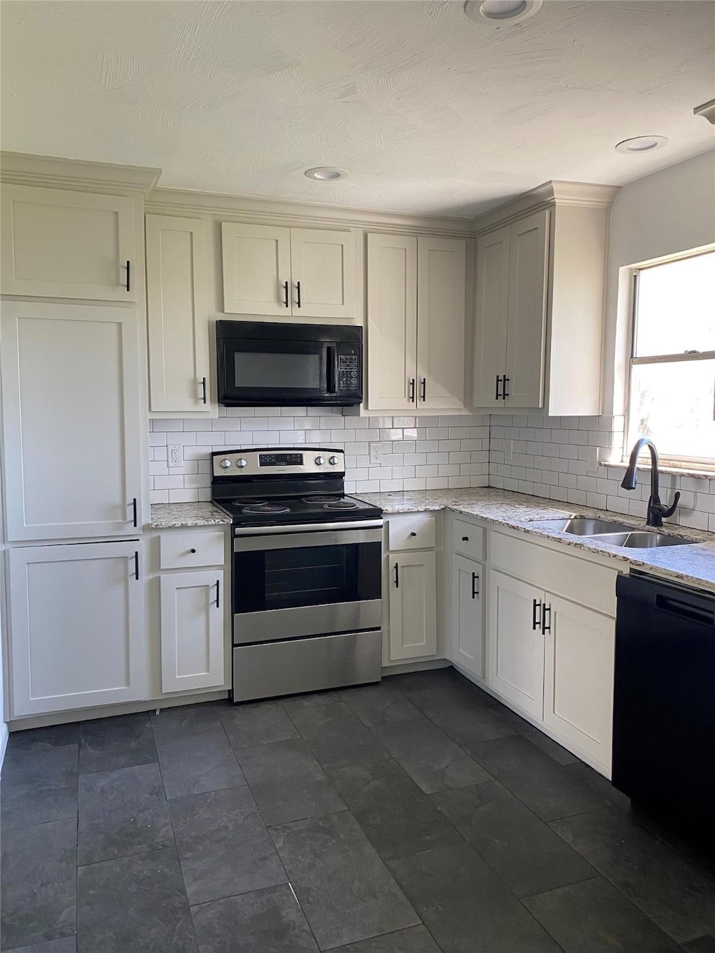 907 W 8th St, Bonham, TX 75418 - kitchen featuring black appliances, a sink, decorative backsplash, and light stone counters