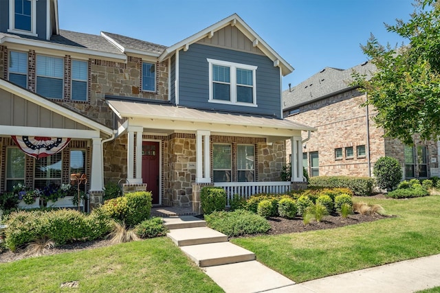 2606 High Cotton Ln, Garland, TX 75042 - view of front facade with stone siding, covered porch, a front lawn, and board and batten siding