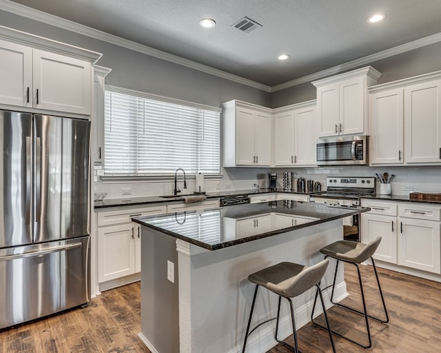513 Dillon St, Waxahachie, TX 75165 - kitchen featuring appliances with stainless steel finishes, a sink, a kitchen bar, a center island, and white cabinetry