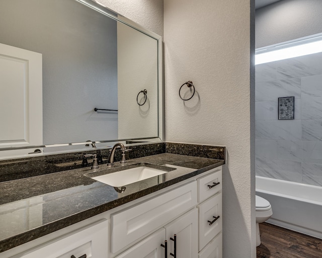 513 Dillon St, Waxahachie, TX 75165 - bathroom with toilet, vanity, wood finished floors, a textured wall, and washtub / shower combination