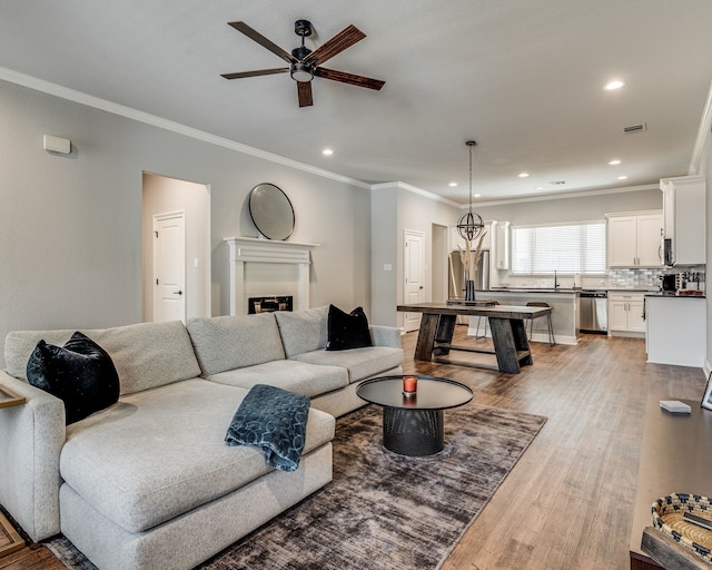 513 Dillon St, Waxahachie, TX 75165 - living room featuring a ceiling fan, ornamental molding, light wood-style floors, recessed lighting, and a glass covered fireplace