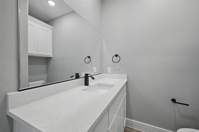 2734 W Washington St, Denison, TX 75020 - half bath featuring toilet, baseboards, vanity, and wood finished floors