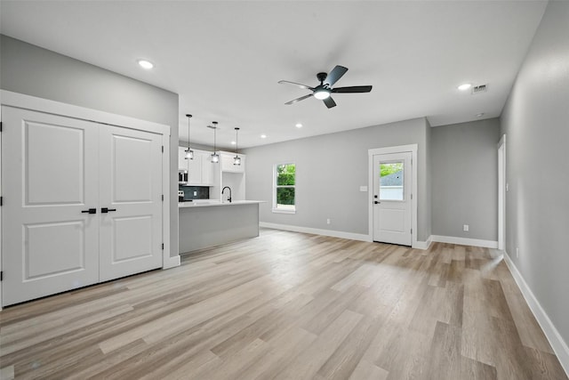 2734 W Washington St, Denison, TX 75020 - unfurnished living room featuring a ceiling fan, light wood finished floors, baseboards, recessed lighting, and a sink