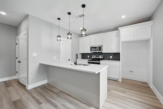 2734 W Washington St, Denison, TX 75020 - kitchen featuring appliances with stainless steel finishes, a sink, light wood-type flooring, a peninsula, and recessed lighting