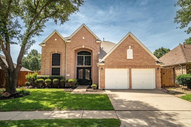 traditional-style house with brick siding, french doors, driveway, and a garage