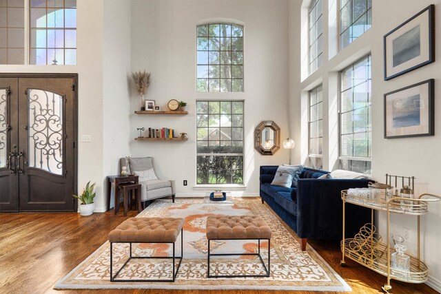 living room with a high ceiling, wood finished floors, baseboards, and french doors