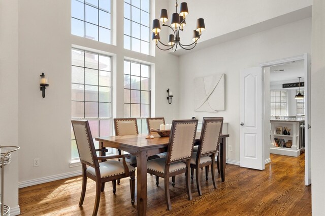 dining space featuring a chandelier, wood finished floors, and baseboards