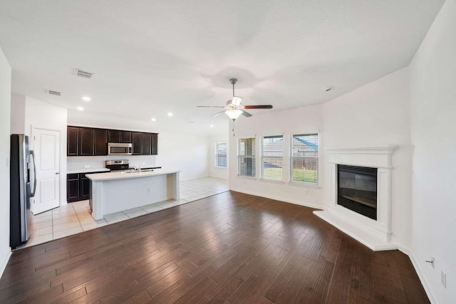 107 Mesa Verde Ct, Forney, TX 75126 - unfurnished living room with light wood-type flooring, a ceiling fan, a glass covered fireplace, recessed lighting, and a sink