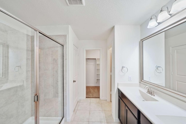 107 Mesa Verde Ct, Forney, TX 75126 - bathroom featuring a stall shower, a textured ceiling, a spacious closet, tile patterned flooring, and double vanity