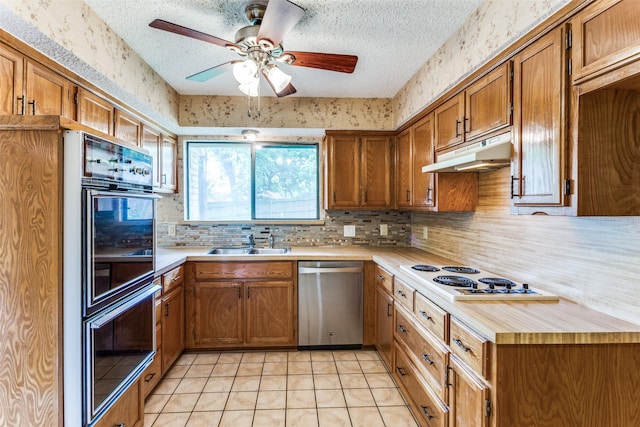 104 NE Rosamond St, Burleson, TX 76028 - kitchen with stainless steel dishwasher, under cabinet range hood, a sink, white electric stovetop, and brown cabinetry