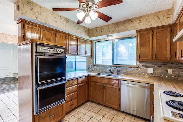 104 NE Rosamond St, Burleson, TX 76028 - kitchen with dishwasher, a sink, double oven, wallpapered walls, and light countertops