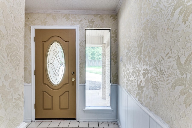 104 NE Rosamond St, Burleson, TX 76028 - entrance foyer featuring wallpapered walls, wainscoting, light tile patterned floors, crown molding, and baseboards