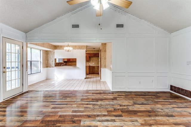 104 NE Rosamond St, Burleson, TX 76028 - unfurnished living room with a decorative wall, wood finished floors, vaulted ceiling, a chandelier, and ceiling fan