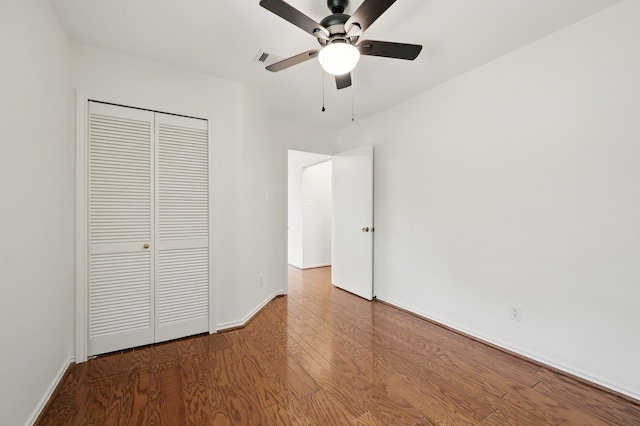 unfurnished bedroom with wood finished floors, a closet, baseboards, and ceiling fan