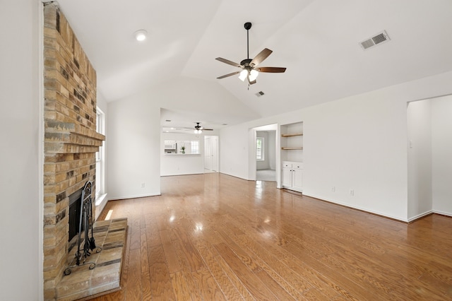 unfurnished living room featuring ceiling fan, vaulted ceiling, a brick fireplace, and wood finished floors