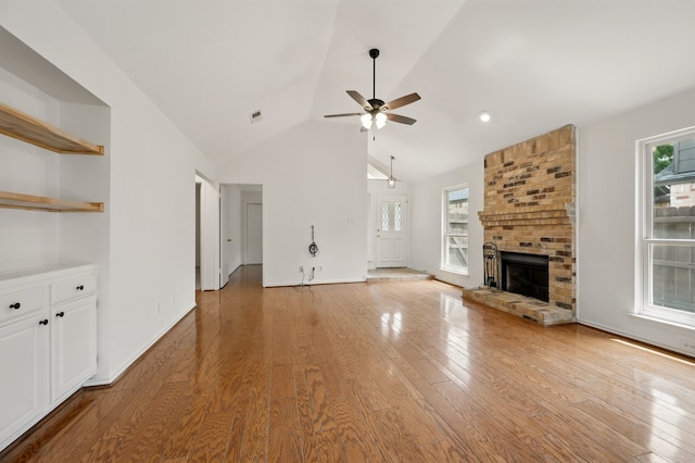 unfurnished living room with ceiling fan, a fireplace, light wood-type flooring, high vaulted ceiling, and baseboards