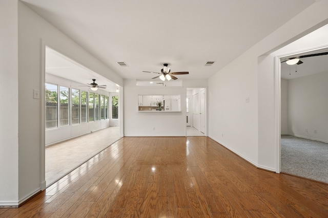 unfurnished living room featuring a ceiling fan, wood-type flooring, and baseboards