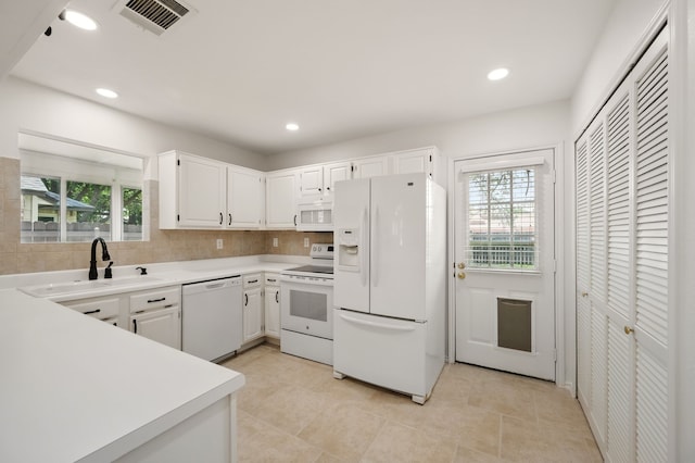 kitchen with white appliances, a sink, healthy amount of natural light, light countertops, and recessed lighting