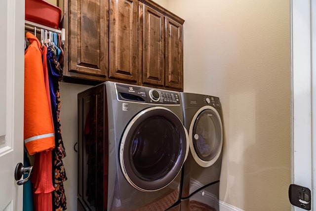 washroom with washing machine and clothes dryer, cabinet space, and baseboards