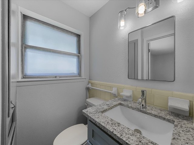 6927 Clearglen Dr, Dallas, TX 75232 - half bathroom featuring toilet, vanity, and tile walls
