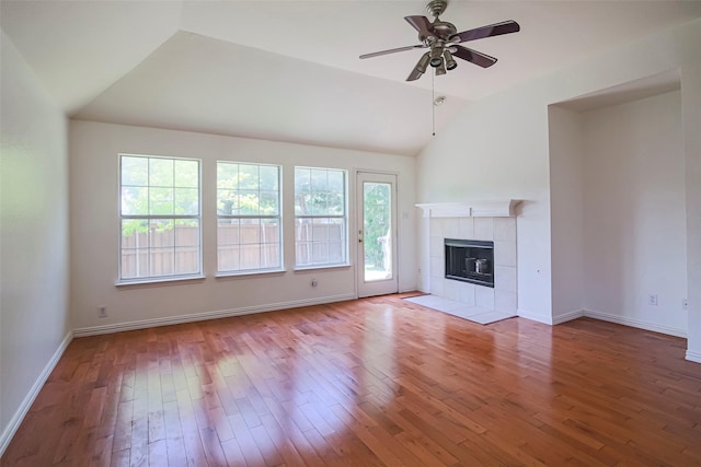 unfurnished living room featuring lofted ceiling, a ceiling fan, hardwood / wood-style floors, a tiled fireplace, and baseboards