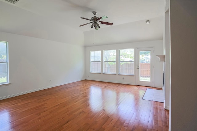 spare room with healthy amount of natural light, lofted ceiling, wood finished floors, a ceiling fan, and baseboards