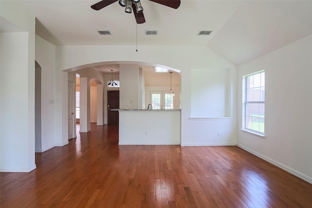 unfurnished living room featuring a ceiling fan, hardwood / wood-style floors, arched walkways, lofted ceiling, and baseboards