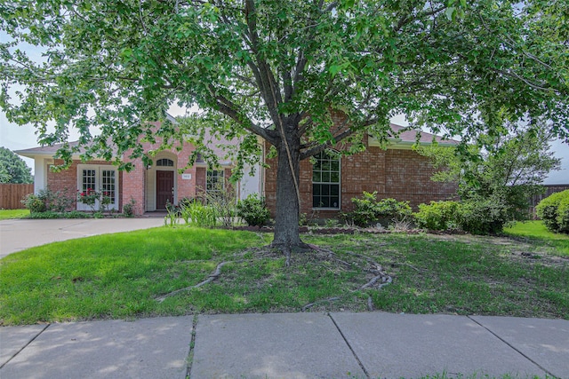 view of property hidden behind natural elements with brick siding