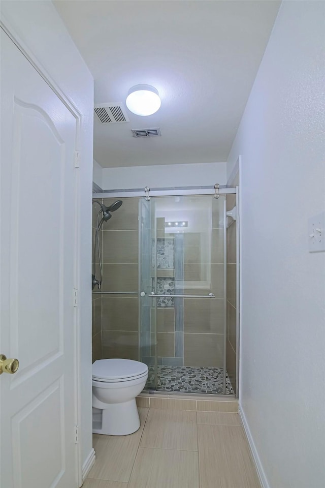 bathroom with toilet, a shower stall, tile patterned floors, and baseboards