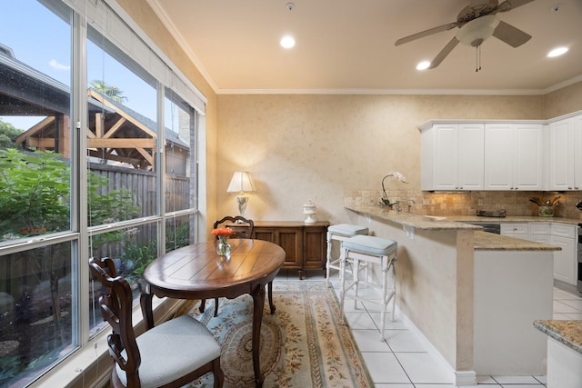 kitchen featuring a peninsula, white cabinets, tasteful backsplash, light tile patterned flooring, and light stone counters